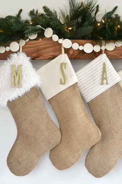 Simple, natural-toned Christmas stockings crafted from burlap, hanging from a rustic mantel.