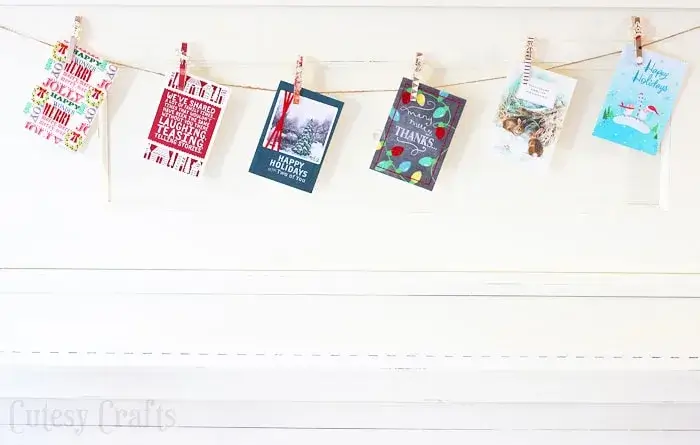 A meaningful strand of DIY Christmas decorations displaying holiday cards from loved ones on a string with small wooden clothespins.