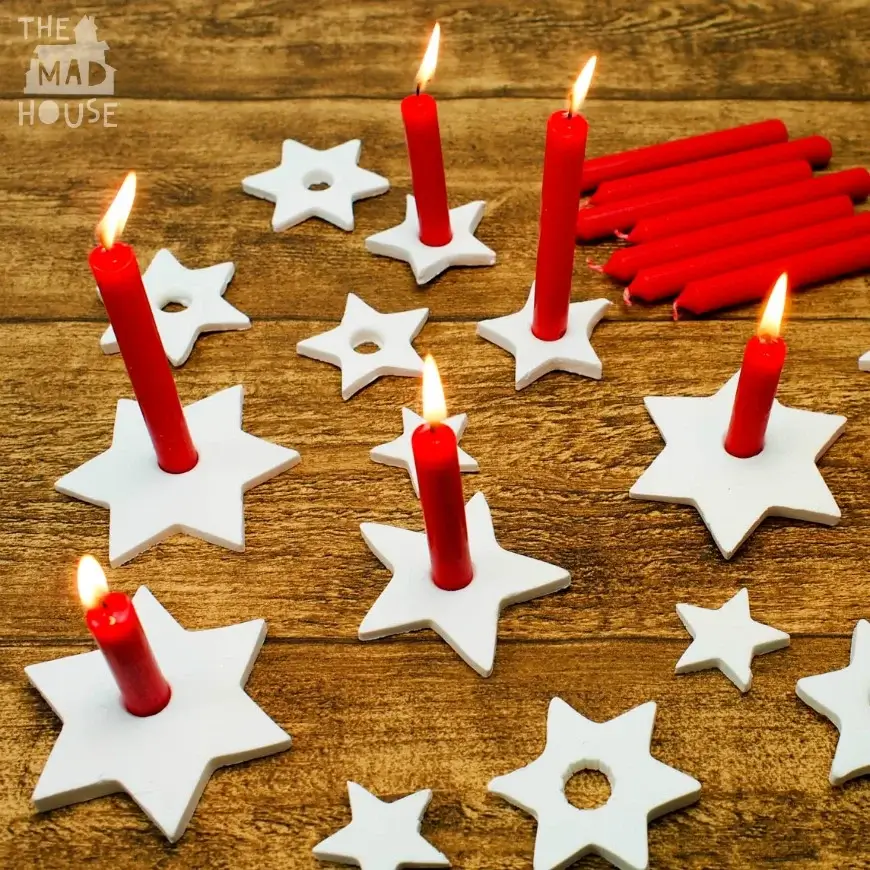Homemade air-dry clay candleholders crafted in star shapes, holding candles for a warm, festive glow.