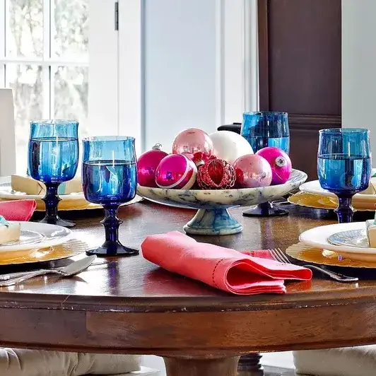 A beautiful apartment Christmas decor centerpiece featuring a cake stand piled high with shiny Christmas ornaments.
