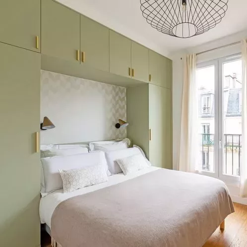 Wall storage behind the bed in a small couple's bedroom.