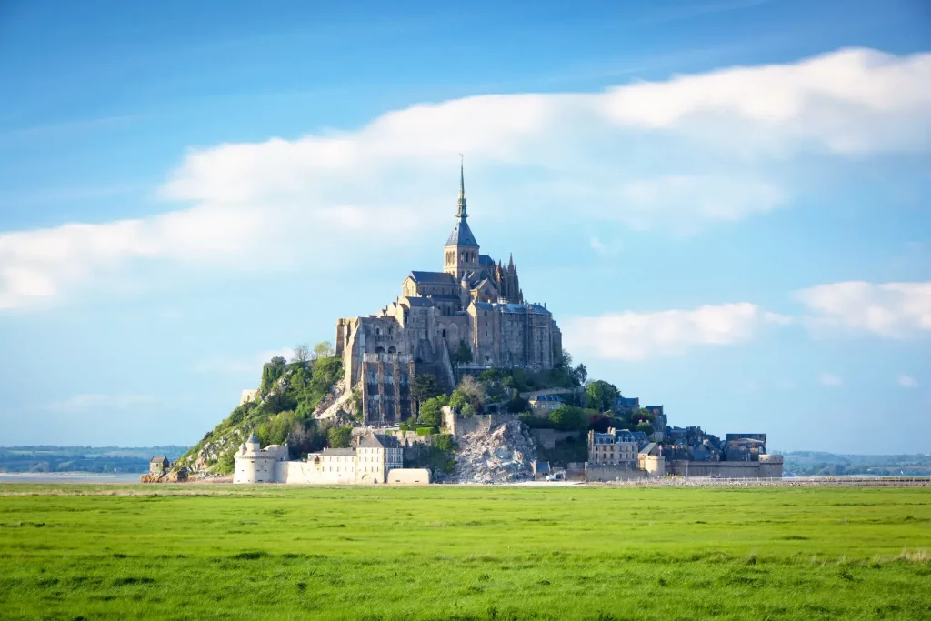 The iconic Mont-Saint-Michel abbey at sunrise over the tranquil bay.