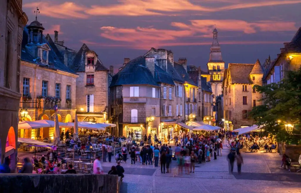 The golden stone buildings and crowded square of the medieval market in Sarlat.