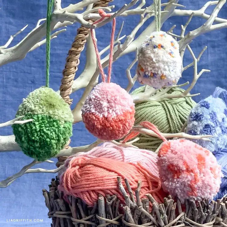 Soft pom-pom egg decorations hanging from spring branches, adding a playful and warm touch to Easter Day and Pinterest Easter decorations