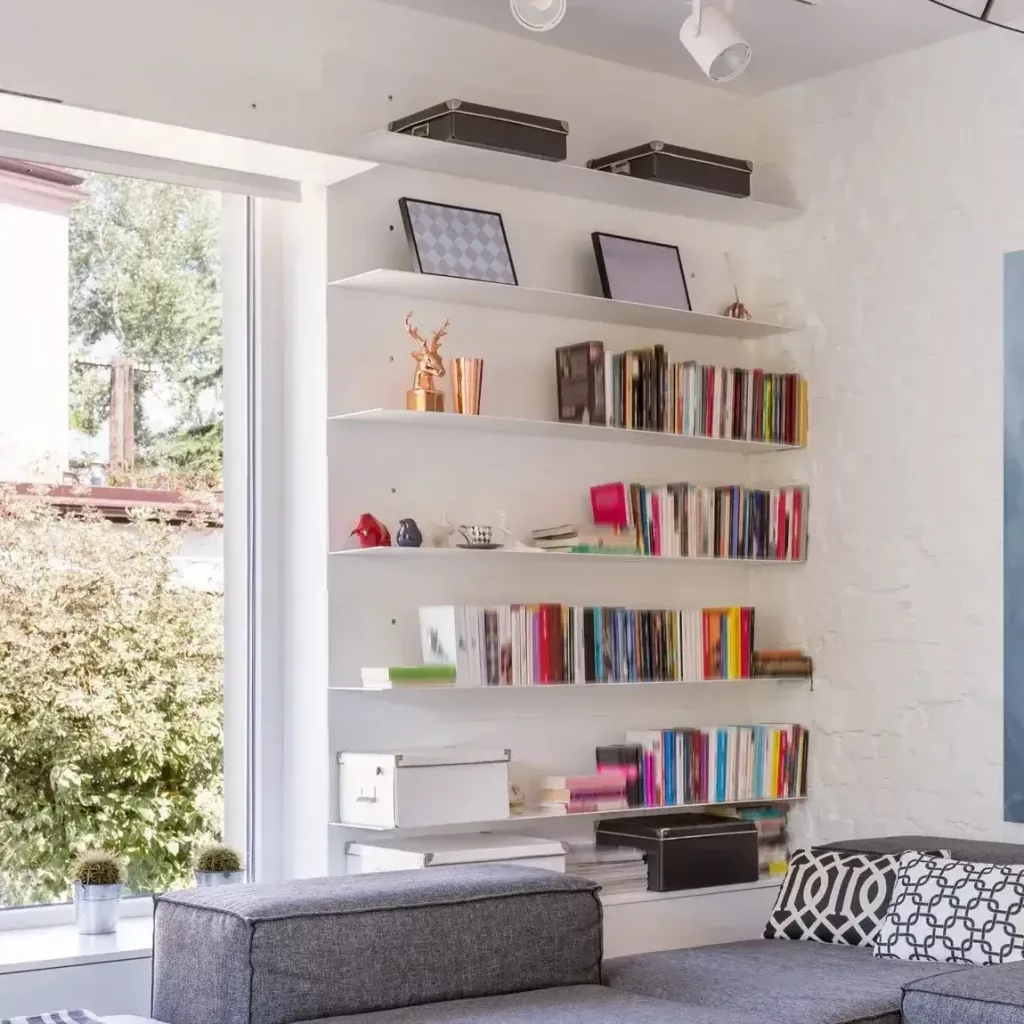 A colorful display of books and decor on floating shelves in a living room 