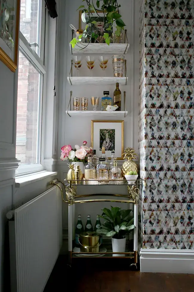 A bar area created with floating shelves and vintage bar cart