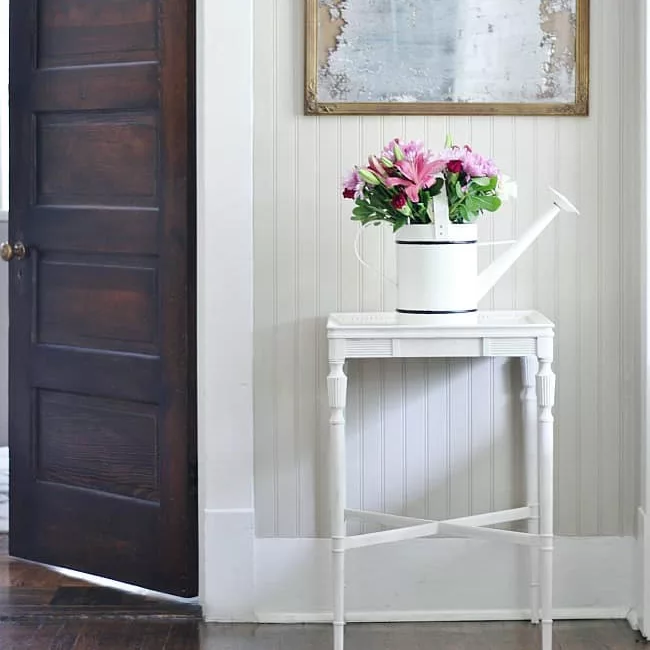 entryway decor with spring blooms in a watering can 