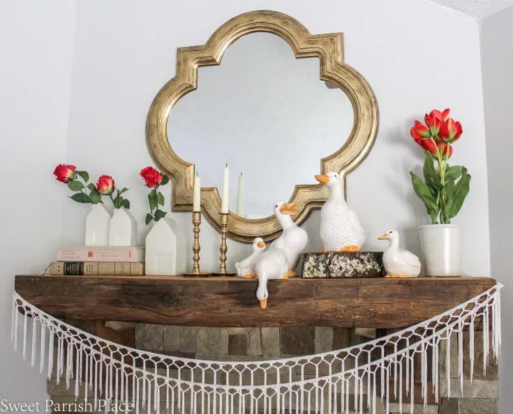 
white houses on a mantel with red spring blooms as spring home decor