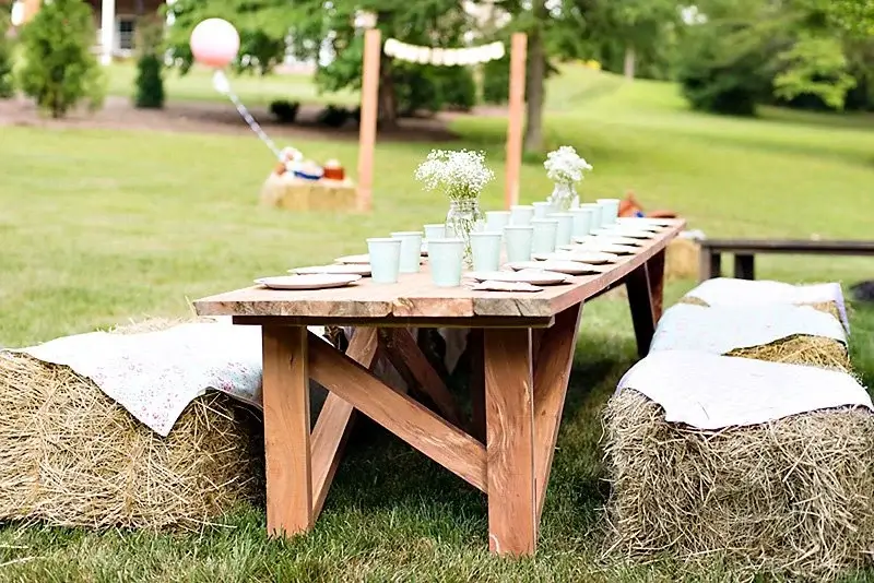 outdoor rustic summer dining table with simple decor and hay bale seating