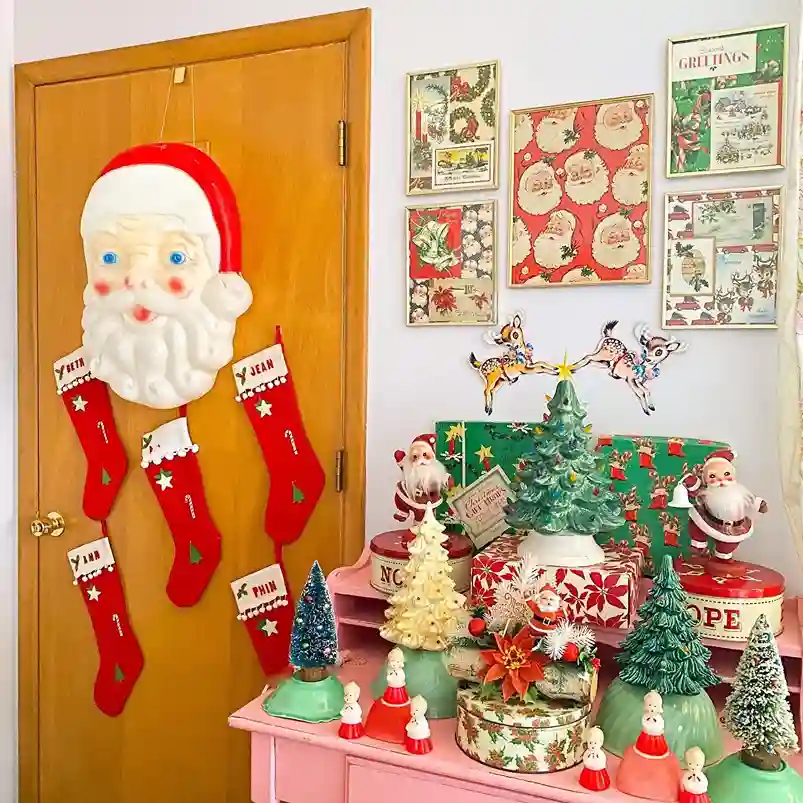 Vintage display of framed crapping paper and cards, cookie tins, plastic vintage Santa face for the door, santas, trees and angle figures
