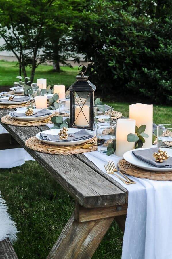 A neutral textured tablecloth with woven charger plates and rustic stoneware dinnerware set on a winter patio table.