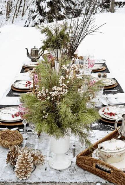  A simple DIY centerpiece made from foraged evergreen clippings, pinecones, and cinnamon sticks on a dining table.