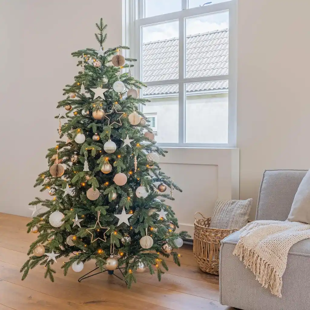 A minimalist Christmas tree decorated with white, cream, and natural wood ornaments