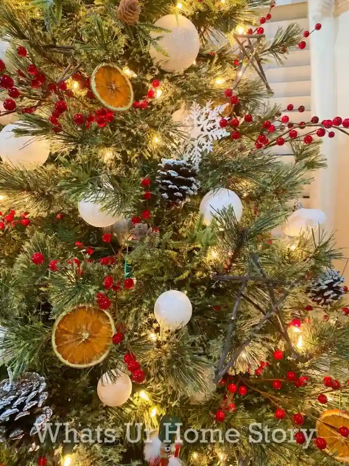 A Scandinavian Christmas decor idea featuring a tree with dried oranges, pinecones, and handmade stick ornaments.