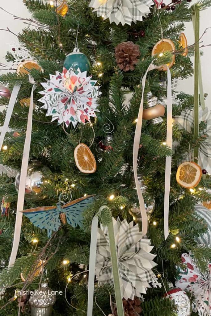  A DIY minimalist Christmas decoration with handmade paper stars and dried orange slices on a tree.