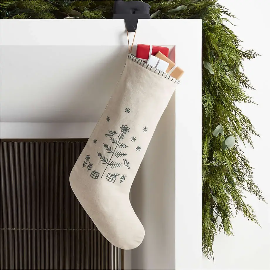 Neutral-colored wool stockings with simple embroidery hanging in a minimalist Christmas home.