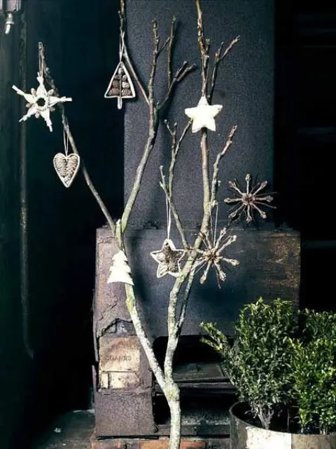 A bare branch spray-painted white and hung with minimalist Christmas tree ornaments as alternative decor.
