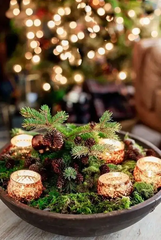 A simple centerpiece of moss with tealight candles for a forest-inspired minimalist Christmas display.