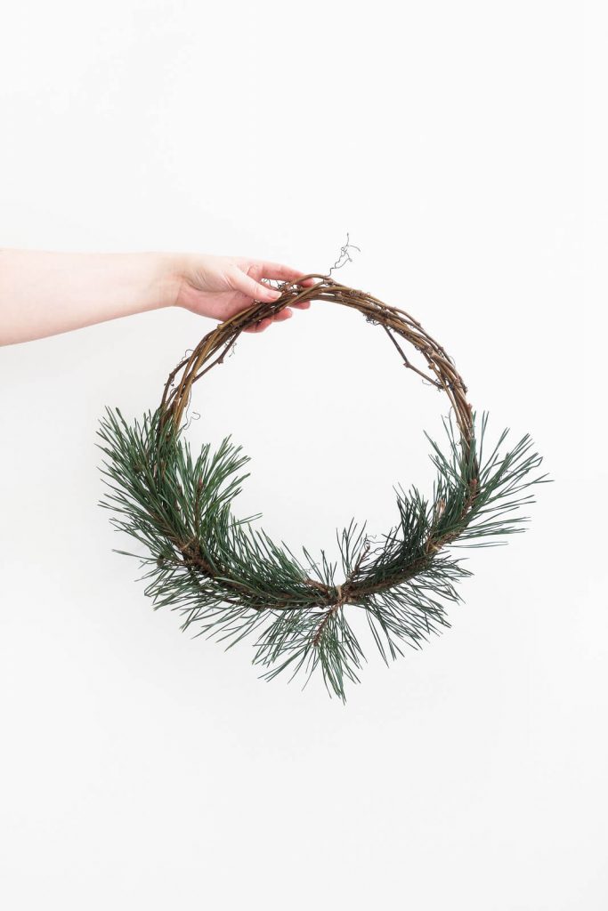 A DIY foraged wreath made of pine and fir on the door of a scandi style home.