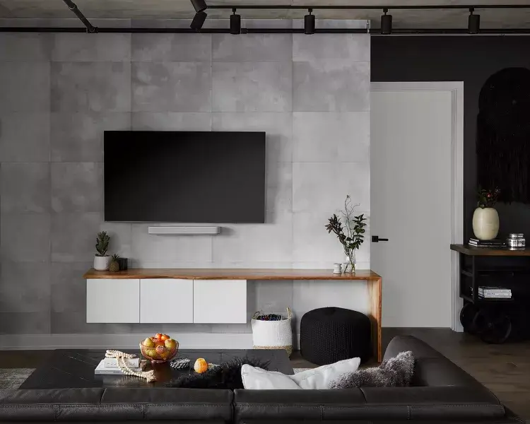 An urban black and white living room where raw concrete and metal are balanced with soft lighting and wood.
