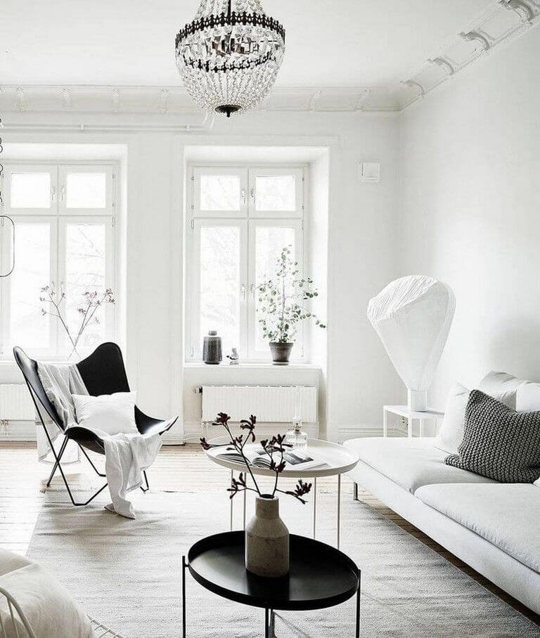 A light-filled Scandinavian living room where a bold black chair punctuates an otherwise airy space.