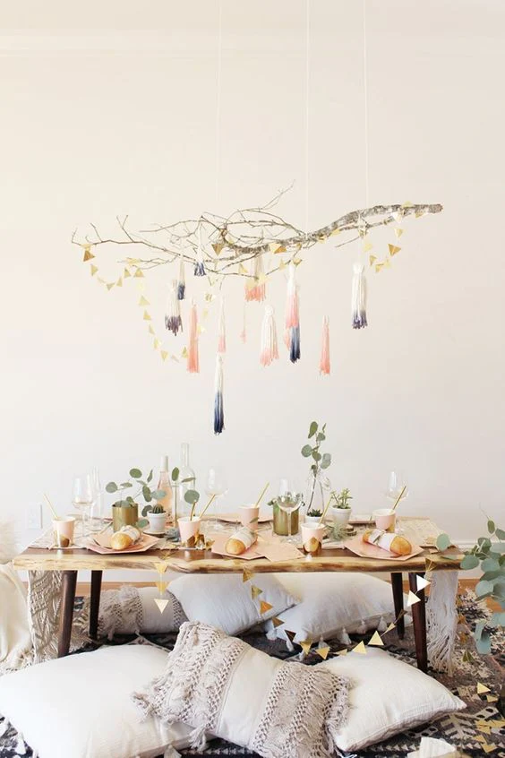 Boho-style festive table decor on a coffee table with floor pillows and macrame for a casual apartment holiday gathering.