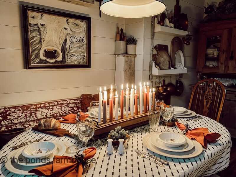 Cozy holiday table settings using a simple row of candles as minimalist festive table decor for a small space.