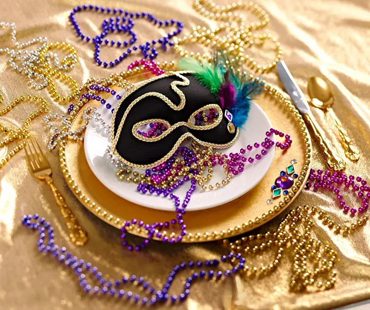 New Year's Eve table decor using masquerade masks and beads as playful festive table decor for a small holiday party.