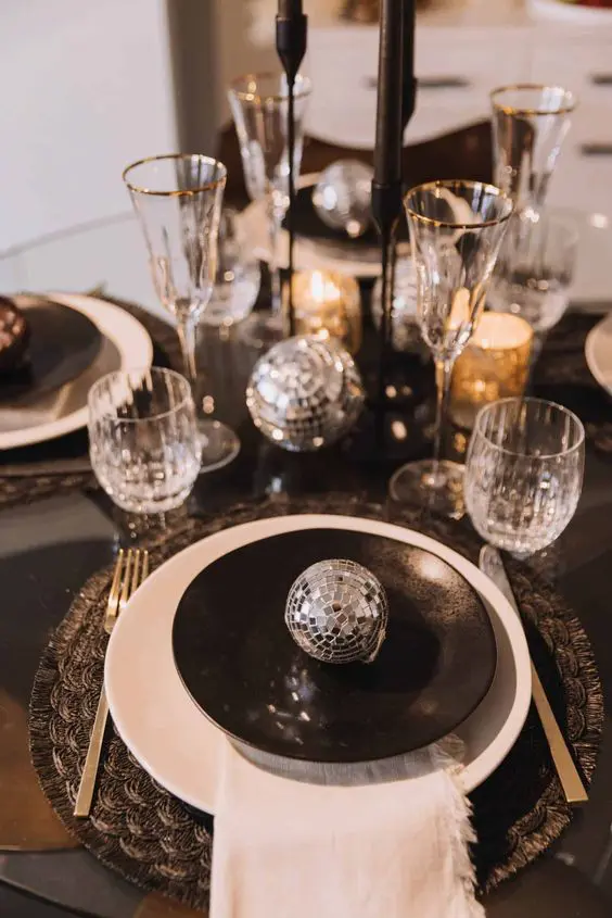 Sparkling New Year's Eve table decor with small disco balls and candles, perfect for an apartment holiday setup.