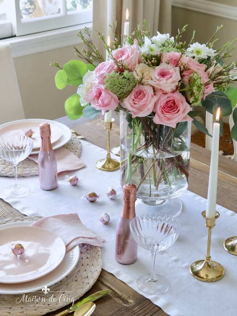 An intimate holiday table setting for two with roses and champagne, showcasing romantic apartment holiday decor.