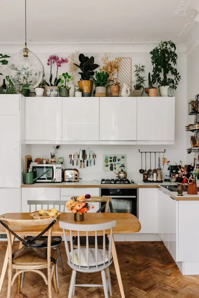 A variety of green plants in help in decorating above cabinets without clutter.