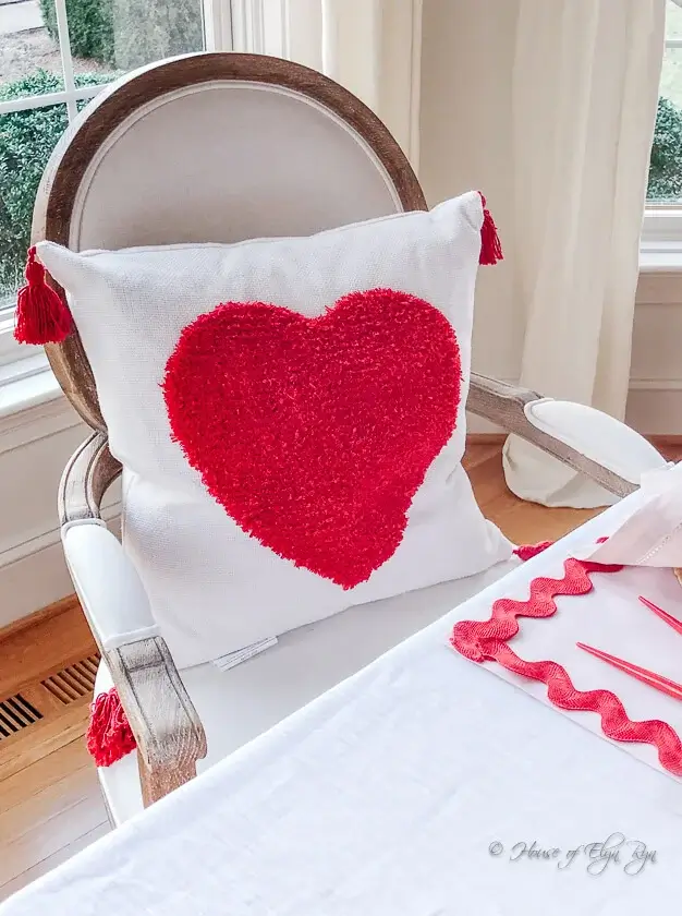Pom-pom cushions on dining chairs for cozy Valentine’s décor