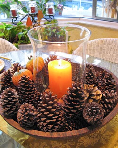 DIY centerpiece using free home decor: pinecones and a candle in a wooden bowl for seasonal natural decor.