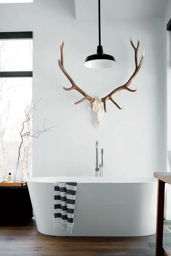 Unexpected use of natural elements in interior design: antlers used as a towel holder in a cabin-style bathroom.

