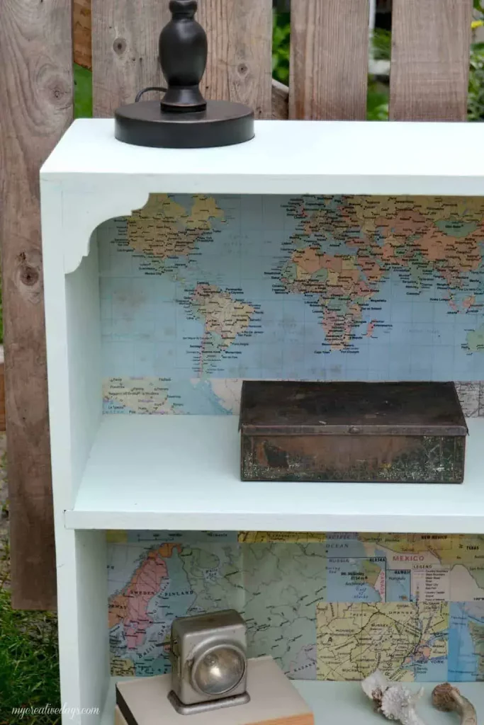 transformed bookshelf with a vibrant map decoupaged to its back panel.