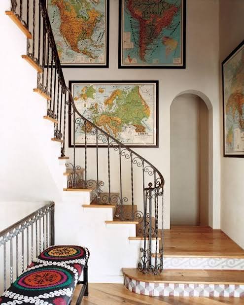 The staircase wall is adorned with an assortment of framed maps;