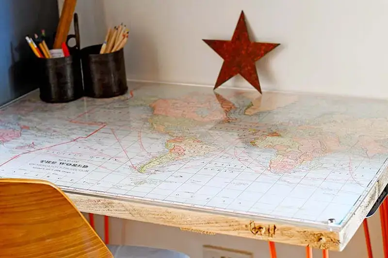 a refurbished desk with a large, beautiful map preserved under a glass top.