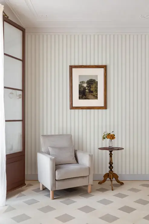 Classic wallpaper with soft neutral pinstripes on a cream background.