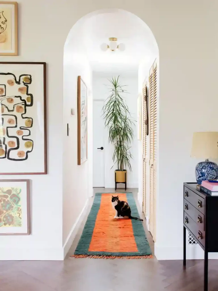 Cozy apartment hallway with a plush runner rug, gallery wall, and layered decor creating cohesive apartment styles.