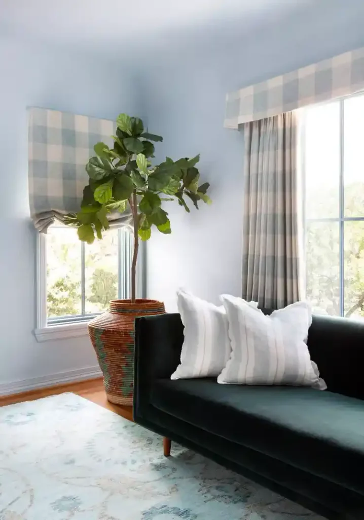 Light blue apartment living room with gingham curtains, striped cushions, and plants for home decor creating a calm apartment style.
