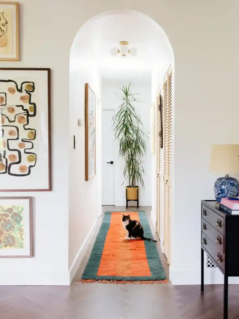 Cozy apartment hallway with a plush runner rug, gallery wall, and layered decor creating cohesive apartment styles.