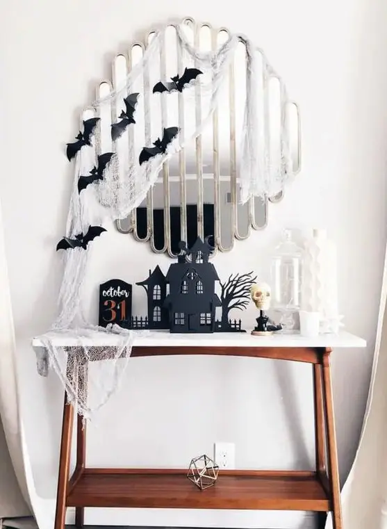 Apartment entryway Halloween decor using a mirror covered in cobwebs and entryway table with Halloween decor